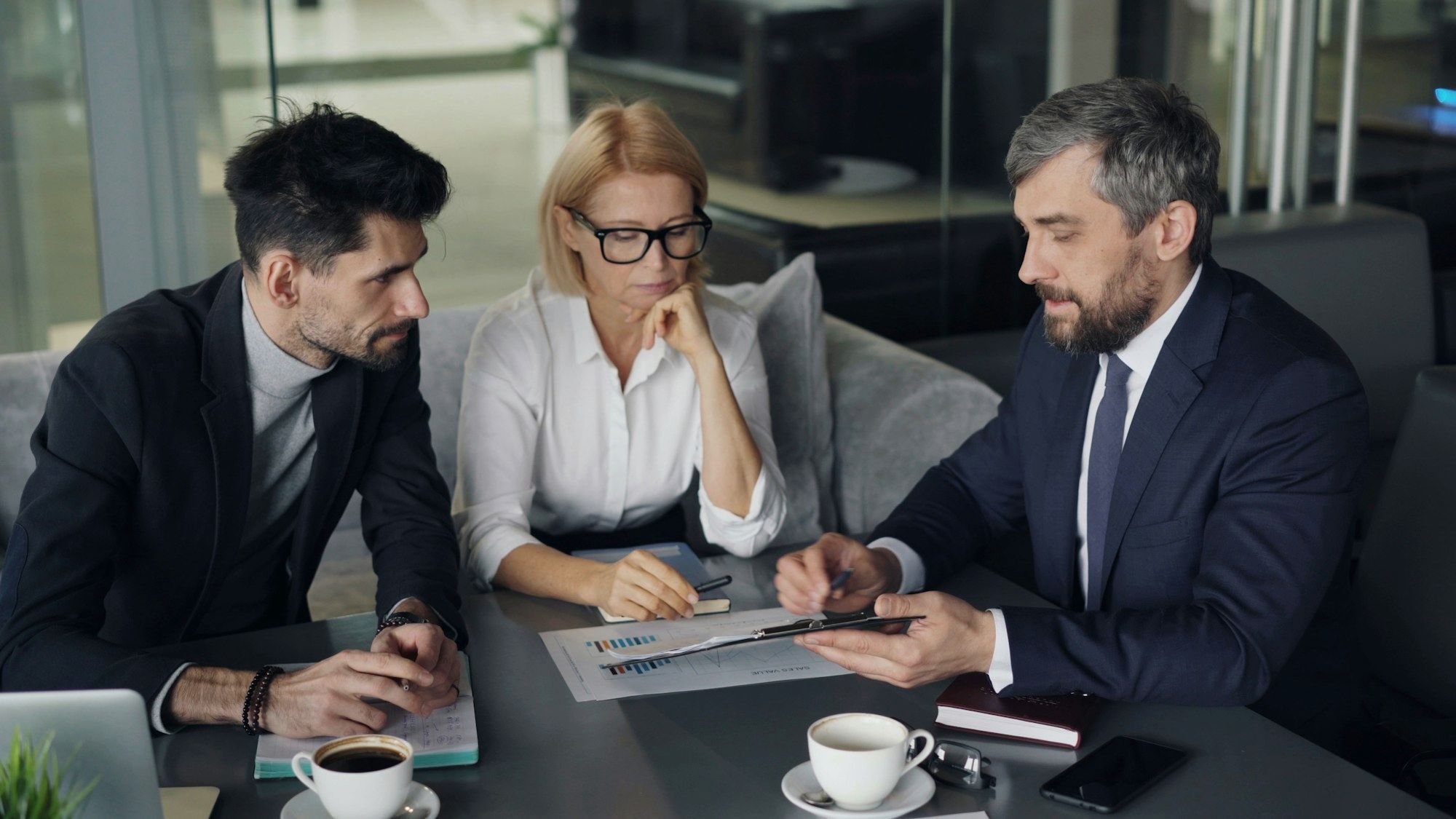 ثلاثة مستشارين يراجعون مستنداً معاً على طاولة اجتماعات