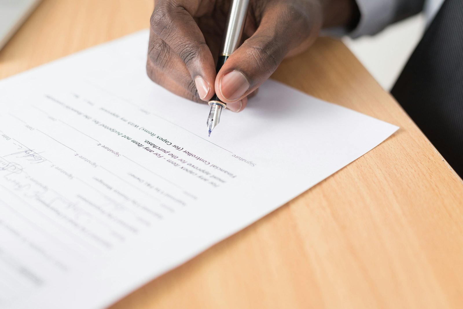 A person signing a document at a desk