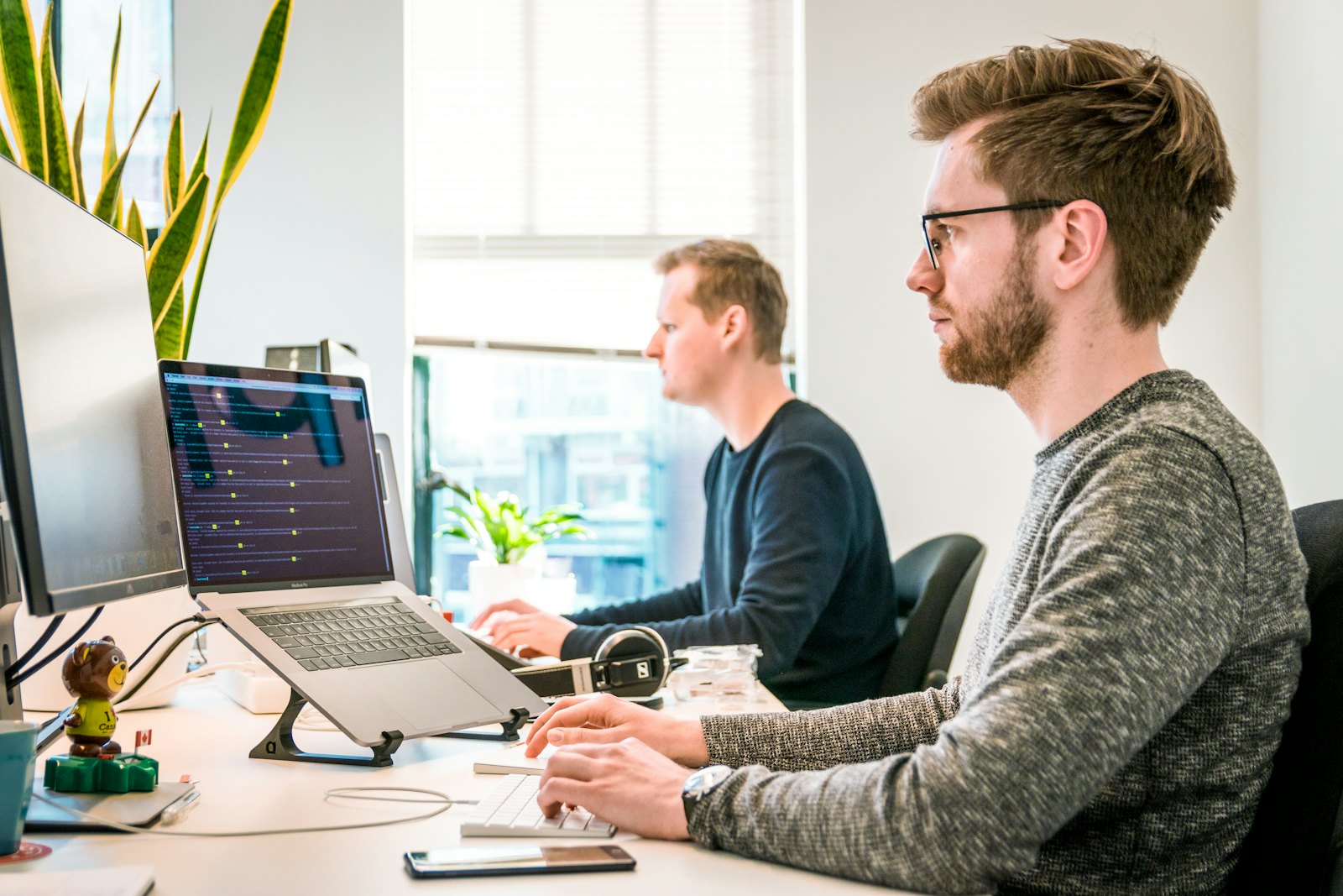 Two colleagues working at laptops in a bright office