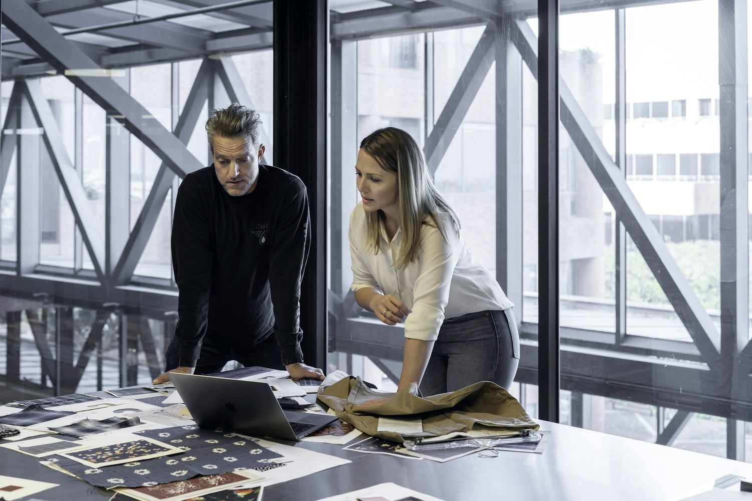 Two people reviewing brand work laid out on a table